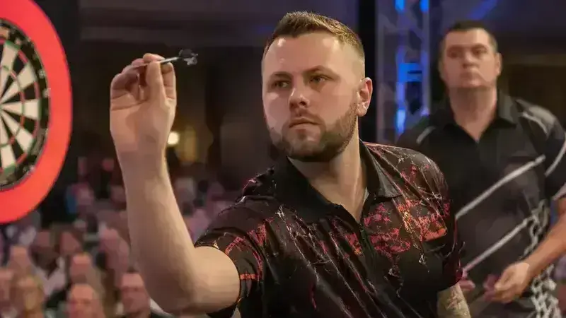 Darts player throwing on a televised stage